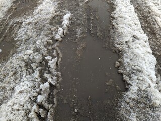 Fototapeta premium melted dirty snow on city streets photo in the daytime.