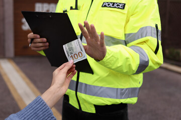 Police officer rejecting bribe outdoors, closeup view