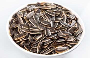 Black sunflower seeds in a bowl on white background