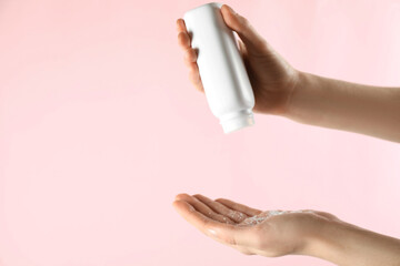 Woman applying dusting powder on pink background, closeup. Space for text