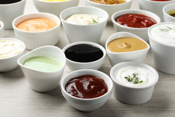 Many different sauces on white wooden table