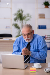 Fototapeta premium Old male employee working in the office