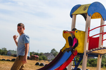 Defocus emotion expression preteen girl slides down the hill on playground with young brunette man,...