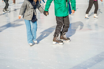 Abstract young couple learning to skate outdoors in skating rink. Winter outdoor activities, sport, leisure