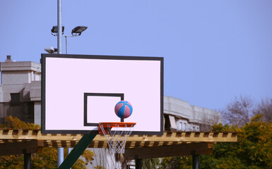 A basketball game, a ball flying into the net.Outdoors.	