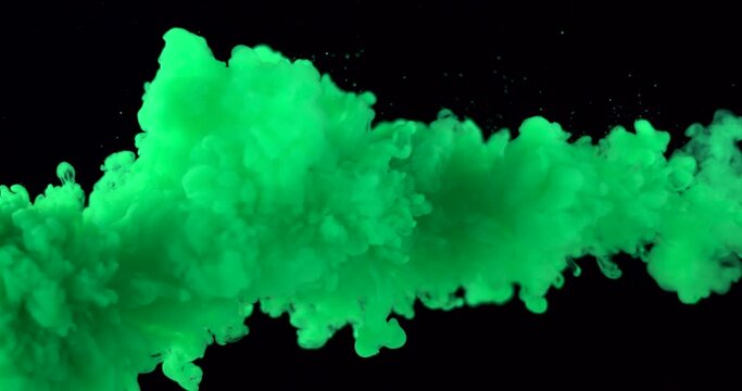 A cloud of green ink or paints in water on a black isolated background.