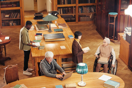 High angle background image of classic library interior with group of diverse people, copy space