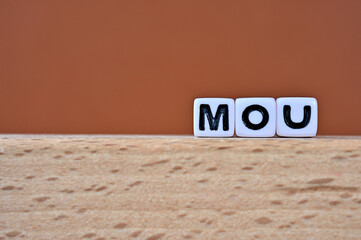 Word cubes lined up with the letters MOU written on it. It is an abbreviation for Memorandum of...