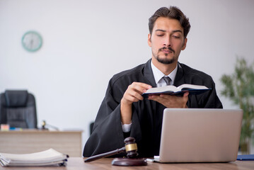 Young male judge reading book in the courthouse