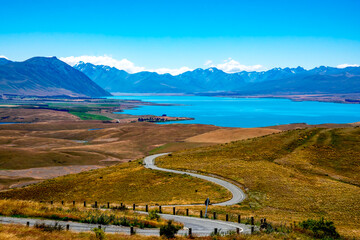 The winding road from the top of Mt John's  Observatory leading to Lake Tekapo and the snow capped Southern Alps - Powered by Adobe