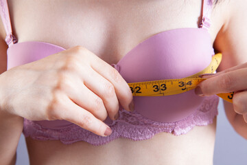 young girl measures breast girth on a gray background