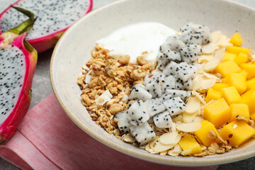 Bowl of granola with pitahaya, mango and yogurt on table, closeup