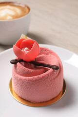 Delicious mousse cake with floral decor on plate, closeup