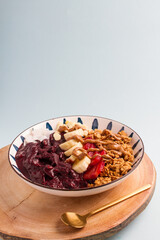 acai bowl with bananas, granola, strawberries, almonds
blue background
