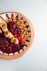 acai bowl with bananas, granola, strawberries, almonds
blue background
