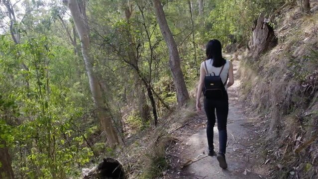 Young woman walking in nature from behind - slow motion wide shot