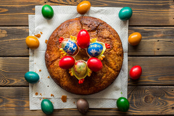 Top view of kozunak (Traditional Easter homemade sweet bulgarian bread) and a circle of colored eggs on a table of wooden planks