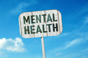 Wooden sign with phrase Mental Health against blue sky on sunny day