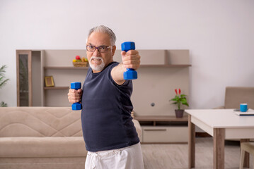 Fototapeta na wymiar Old man doing sport exercises at home