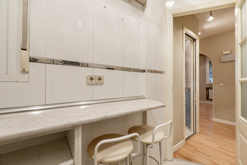 Dining area with two stools in small apartment kitchen with white woodwork