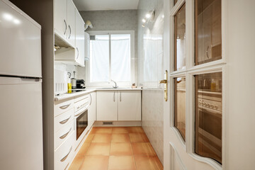 covered kitchen with white wooden cabinets, white wooden countertop, black ceramic hob, microwave, oil can and small appliances