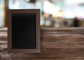 Small blank chalkboard on wooden table indoors. Mockup for design