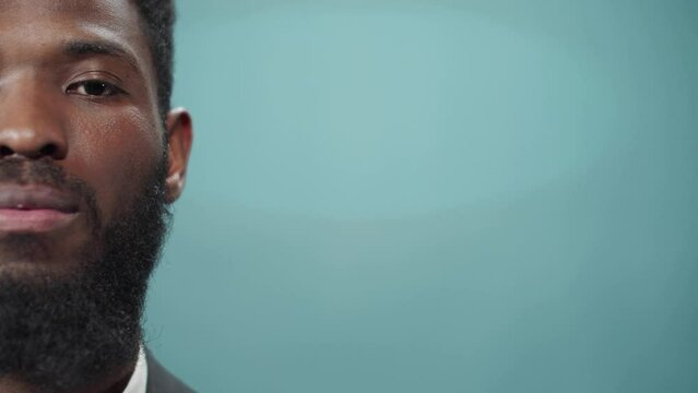 A young african bearded man is looking to the camera seriousness 