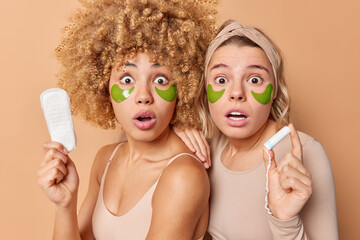 Shocked startled women stare surprised at camera hold sanitary napkin and tampon cannot believe her eyes dressed casually isolated over beige background. Hygiene menstruation skin care concept