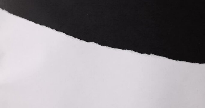 A white paper is torn on a black background.