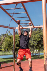 Fototapeta premium Vertical photograph of a man crossing the brachiation ladder or monkey bar