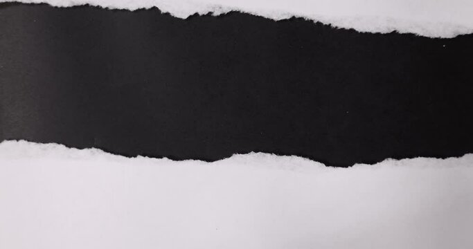 A white paper is torn over a black background.