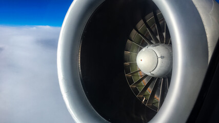 Close-up of Jet Engine Flying Over Clouds with Blue Sky 