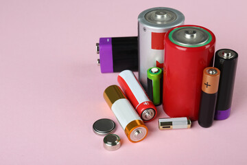 Different types of batteries on pink background, space for text - obrazy, fototapety, plakaty
