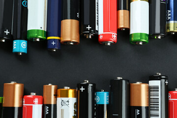 Many different batteries on black background, flat lay - obrazy, fototapety, plakaty