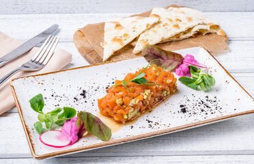 salmon Tartar on a plate on white wooden table