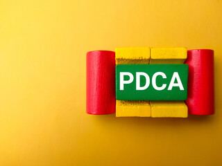 Top view colored wooden block with text PDCA on a yellow background.