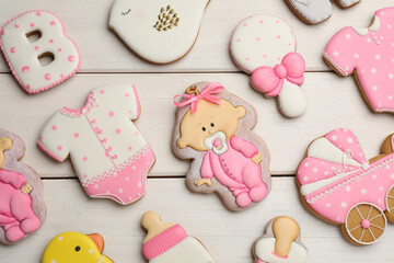 Cute tasty cookies of different shapes on white wooden table, flat lay. Baby shower party