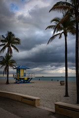 Obraz premium A view towards the beach from the Hollywood, Florida boardwalk with lifeguard observation shelter between silhouettes of tall palm trees