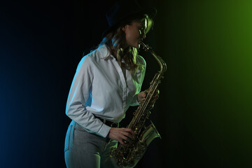 Fototapeta na wymiar Beautiful young woman playing saxophone on dark background