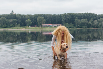 Young woman playing with her labrador retriever dog in river.