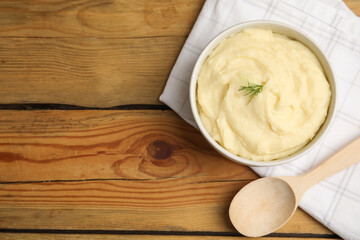 Freshly cooked homemade mashed potatoes, spoon and napkin on wooden table, flat lay. Space for text