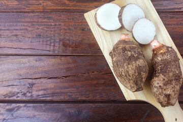 raw yam over rustic wooden table. Also known as Alocasia, Colocasia, Xanthosoma