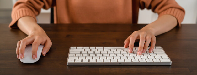 Close up of hand press the button computer mouse and type text on keyboard on table.