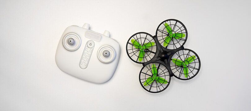 A small compact copter and a white remote control on a light background.Toys for indoor flight.Racing drone.