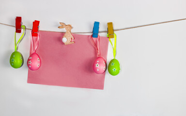 Easter eggs and blank card hanging on the clothesline isolated on white