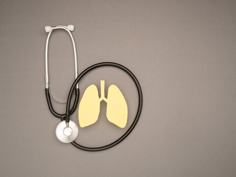Yellow paper lungs and a stethoscope on a gray background