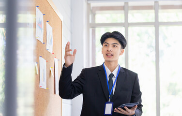 Selective focus at hand, Business man making a presentation in front of board, male employee explains business data on board in office room