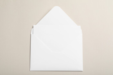White paper envelope with blank card on beige background, top view