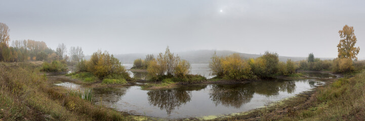 Fototapeta na wymiar panorama of fog over the river with relief bushes in the foreground at dawn in autumn
