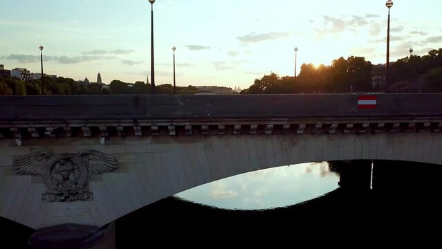 Aerial moving along and facing the I&eacute;na bridge then Eiffel Tower, at sunrise, over seine river. Close, sun facing.